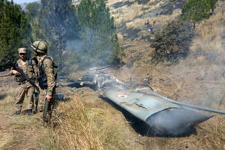 Pakistani soldiers stand next to what Islamabad says is the wreckage of an Indian fighter jet shot down in Pakistan- controlled Kashmir