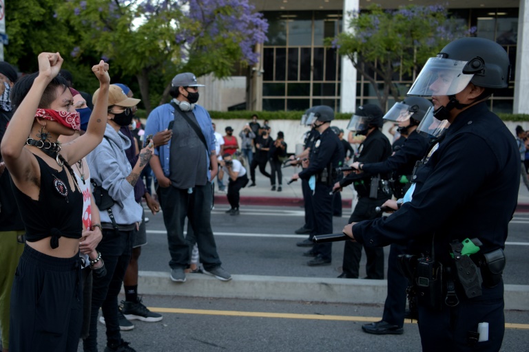 Protesters hold up their fists in front of a row of police officers in downtown Los Angeles to demonstrate over the police killing of George Floyd in Minneapolis